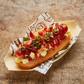 Hotdog met aardappelsalade en spek