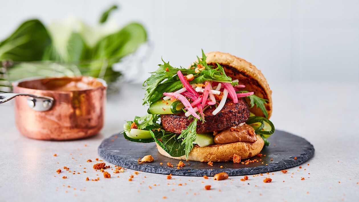 Vegetarische burger met zoetzure komkommer, taugé, krokante pinda en satésaus – Recept