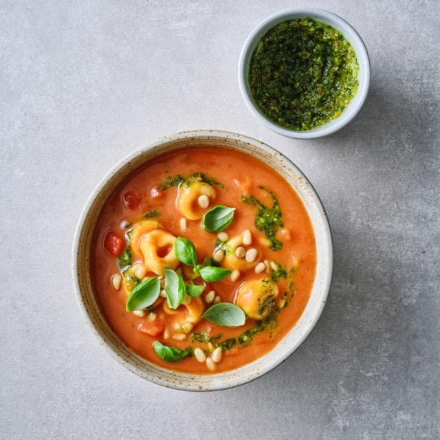 Italiaanse tomatensoep met tortellini, pesto en basilicum