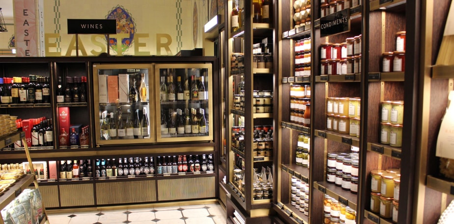 De binnenkant van een winkel, er staan flessen wijn/bier en potjes met sauzen