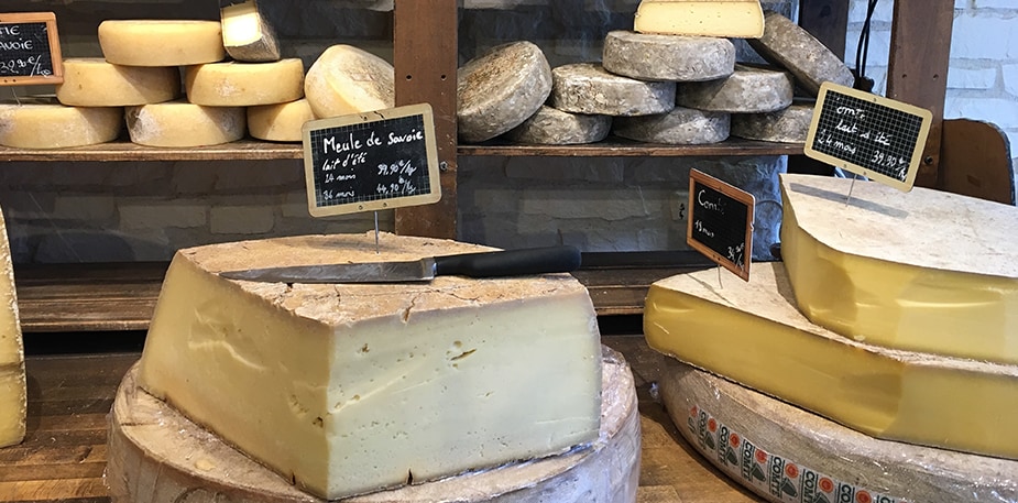 Een Franse kaaswinkel met enkele stukken kaas op de grond en in de kast