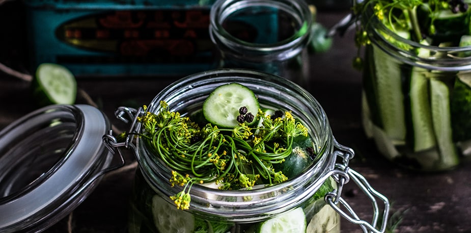 Glazen potten met deksel. De potten bevatten reepjes komkommer en kruiden